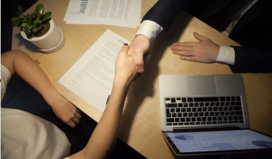 Business professionals shaking hands over a table, signifying a successful career transition or partnership.